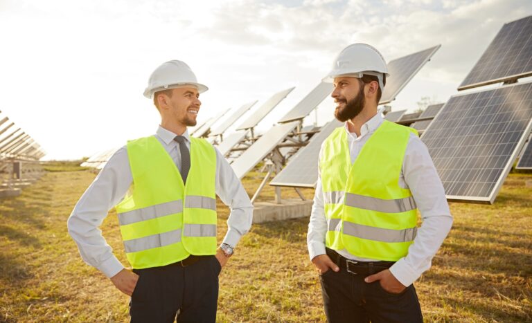 Smiling engineers in field with photovoltaic panels